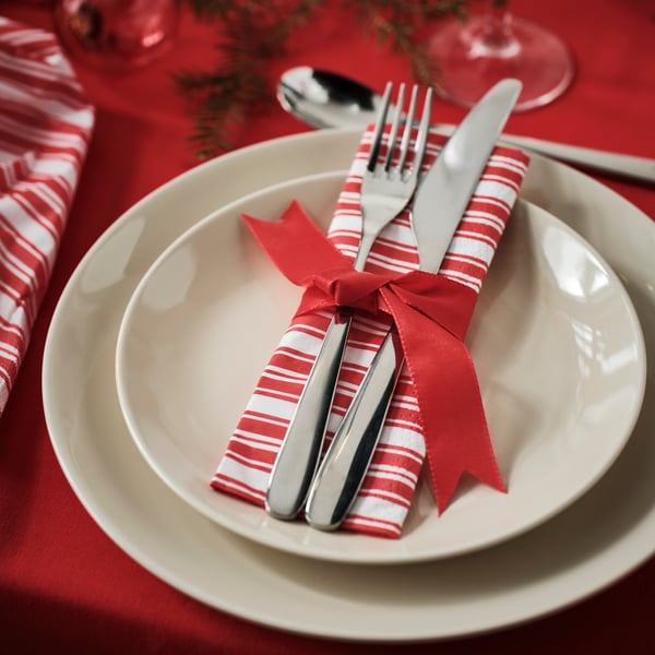 Dos platos blancos uno de fondo y otro de pan, uno sobre otro y sobre el plato de pan una servilleta de navidad VINTERFINT y dos cubiertos IKEA.