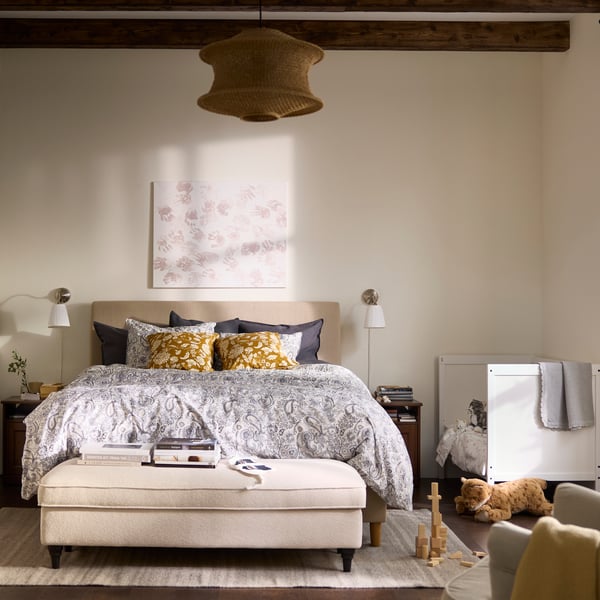 Camera da letto nei toni del bianco e del beige, con un lettino a lato del lettone e una poltrona in primo piano.