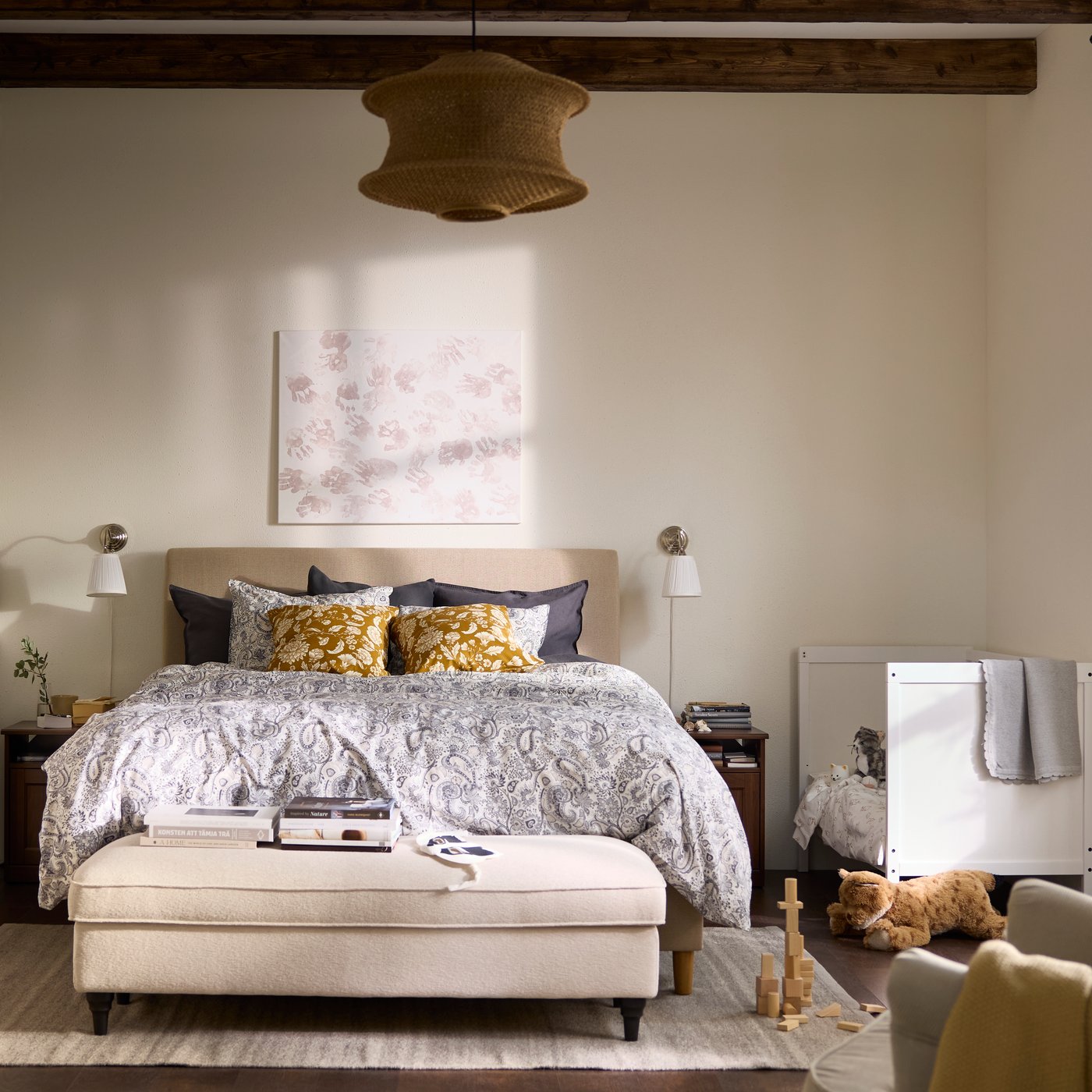 Bedroom in all beige and white with a children’s bed next to the grown-up’s bed, and an armchair in the foreground.