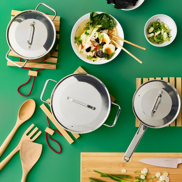A green kitchen countertop featuring multiple GULDÖRING pots with stainless steel lids by a food dish and a cutting board.