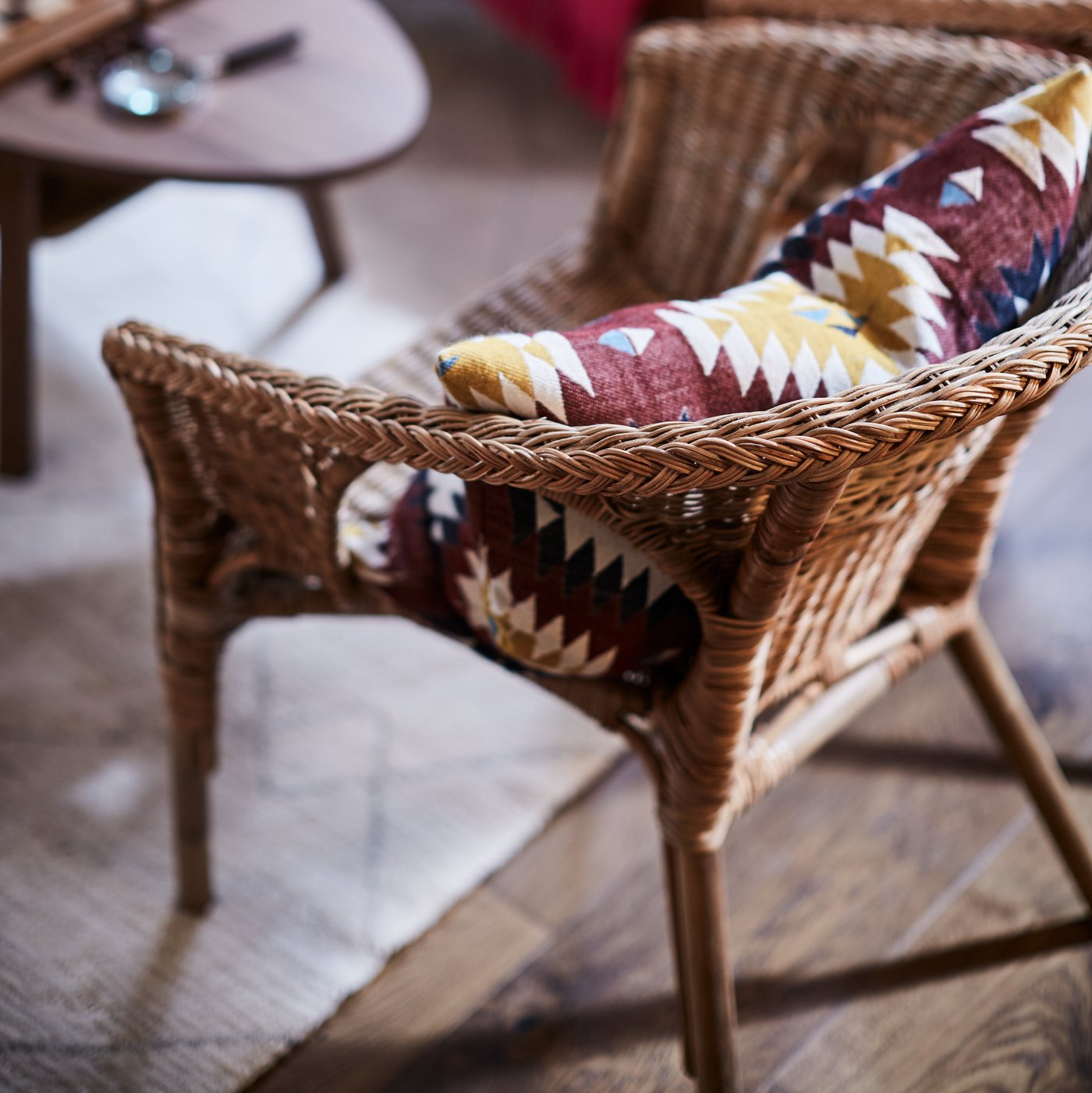 An AGEN armchair in rattan and bamboo with a cushion resting in its seat.