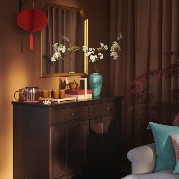 Rantaian pencahayaan LED FÖSSTA tergantung di atas buah-buahan pilihan dalam pinggan FÖSSTA berwarna kuning.