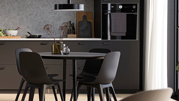 Een zwarte keuken met een zwarte ronde eettafel en vier zwarte ODGER eetakmerstoelen eraan.