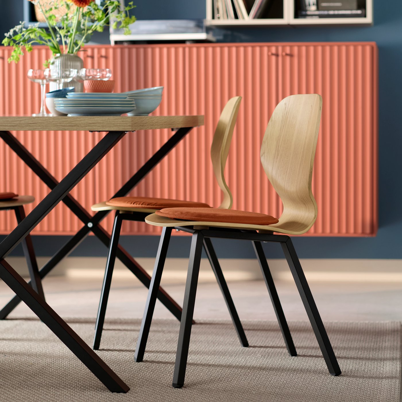 Zwei SKÅLSTA Stühle mit Sitzschalen aus Eiche Furnier und schwarzen Beinen stehen Weiter einem SKÅLSTA Tisch in passenden Farben.