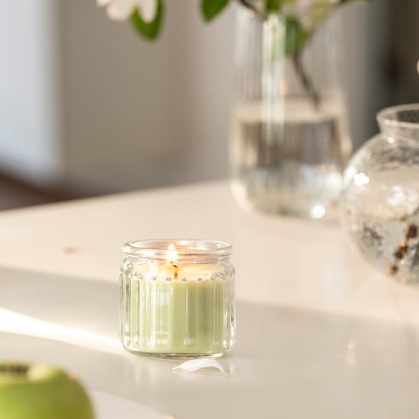 An apple/light yellow LÖVSKOGSLUND scented candle in glass