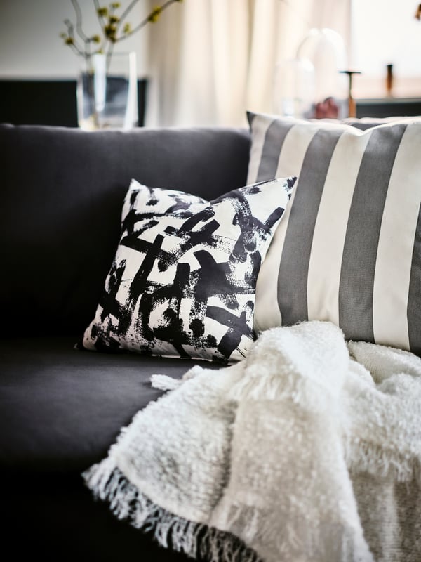 Een zwart/witte kussen TURILL op een bank
