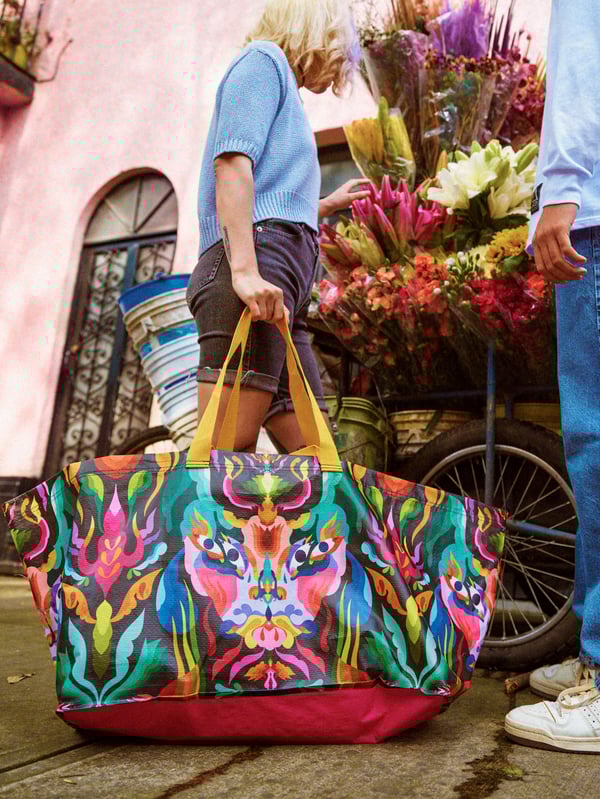 Two young people standing next to a flower cart. One of them is carrying a multicoloured ÖMSESIDIG carrier bag.
