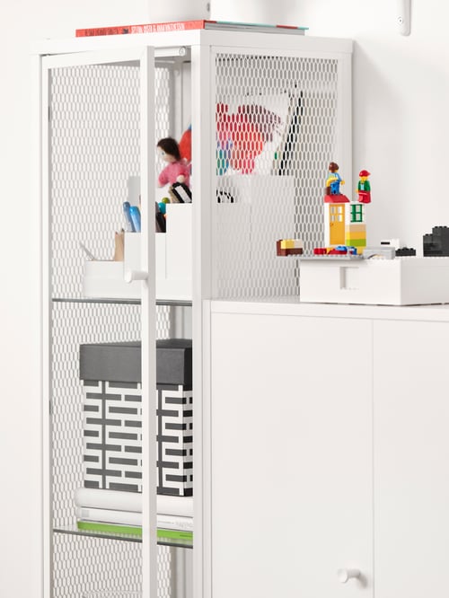 Ein weißer Schrank mit Glastüren, ein weißer Schrank mit Tür, ein weißes Schreibutensilienfach, Bastelmaterialien, Spielzeug.