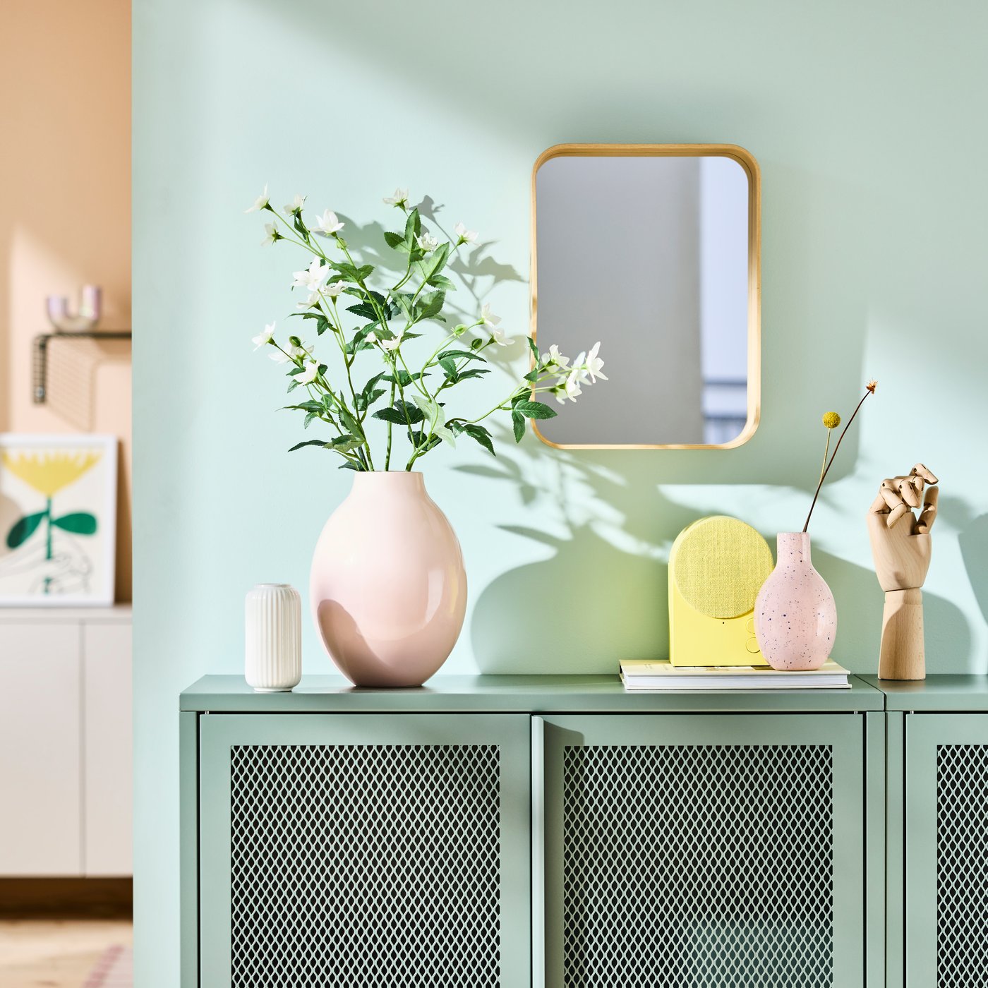 Vázy a dekorace na zelené komodě.