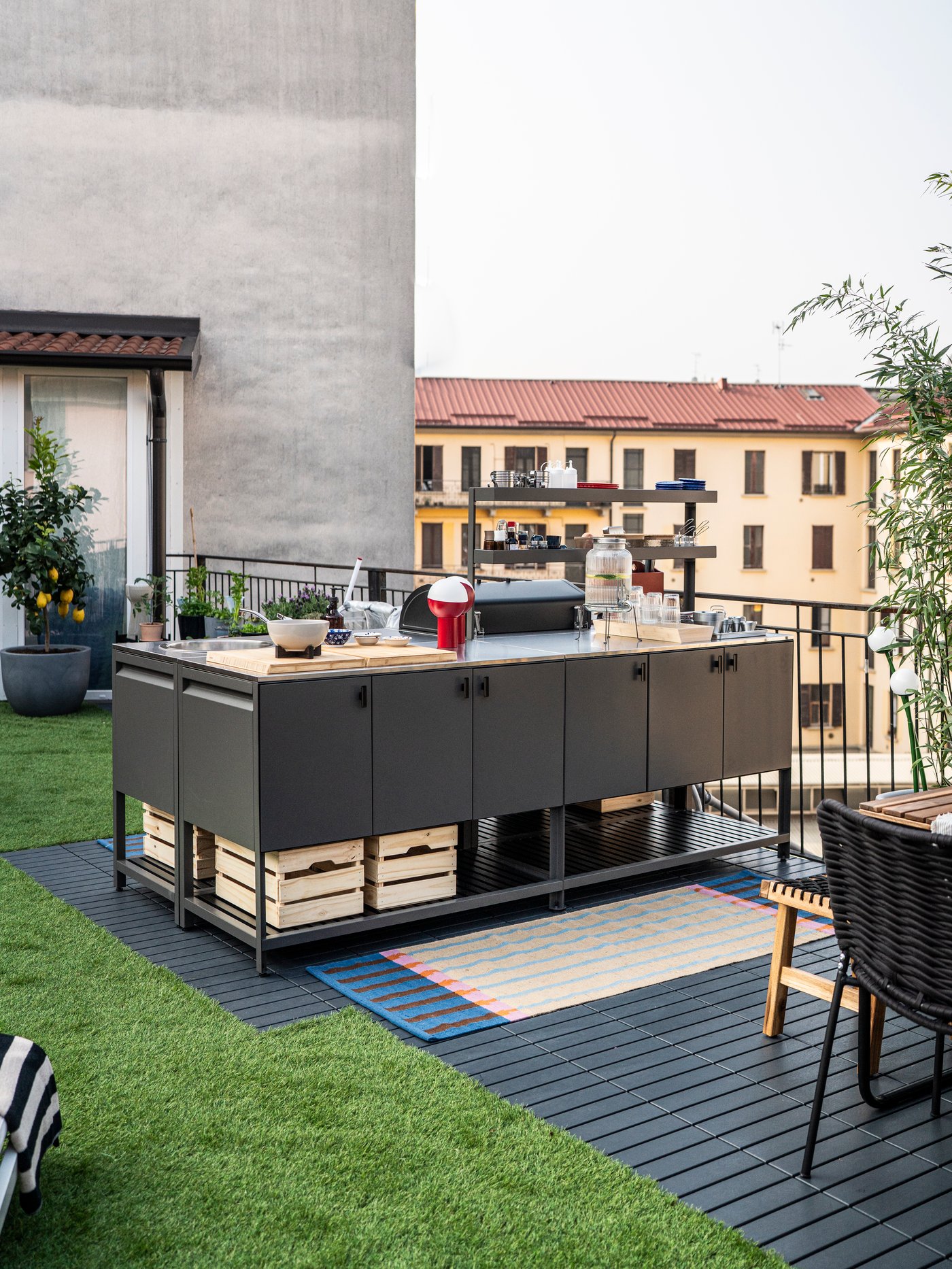 Spazio esterno con cucina esterna compresa BBQ a carbone grigio scuro, davanti una tappetto MÄVINN a tessitura piatta, beige a righe.