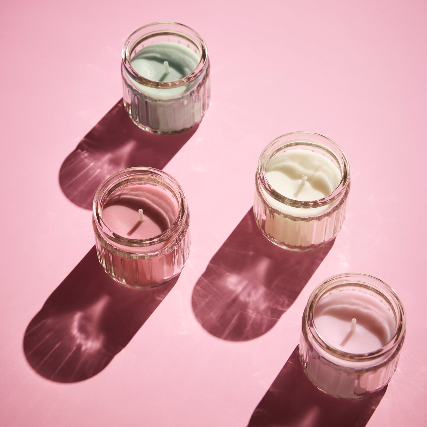 Four HÖKGÖK scented candles in the colours of apple, pink flowers, red berries and vanilla.