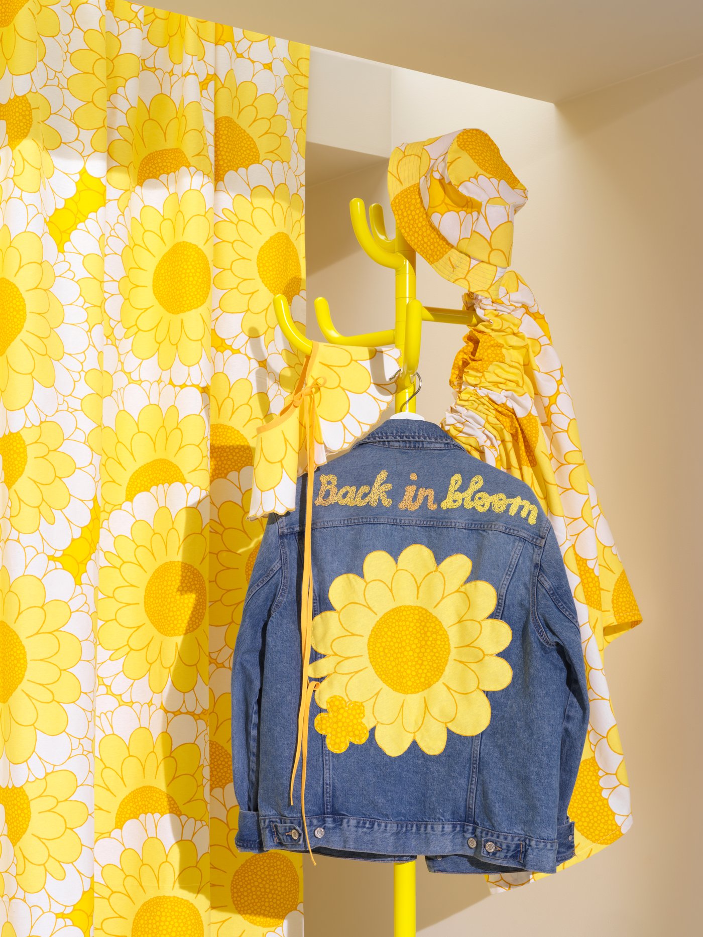 Topi dan skirt yang dibuat daripada fabrik prapotong 3 meter SANDETERNELL berwarna kuning dengan jaket denim tergantung pada penyangkut kot berwarna kuning.