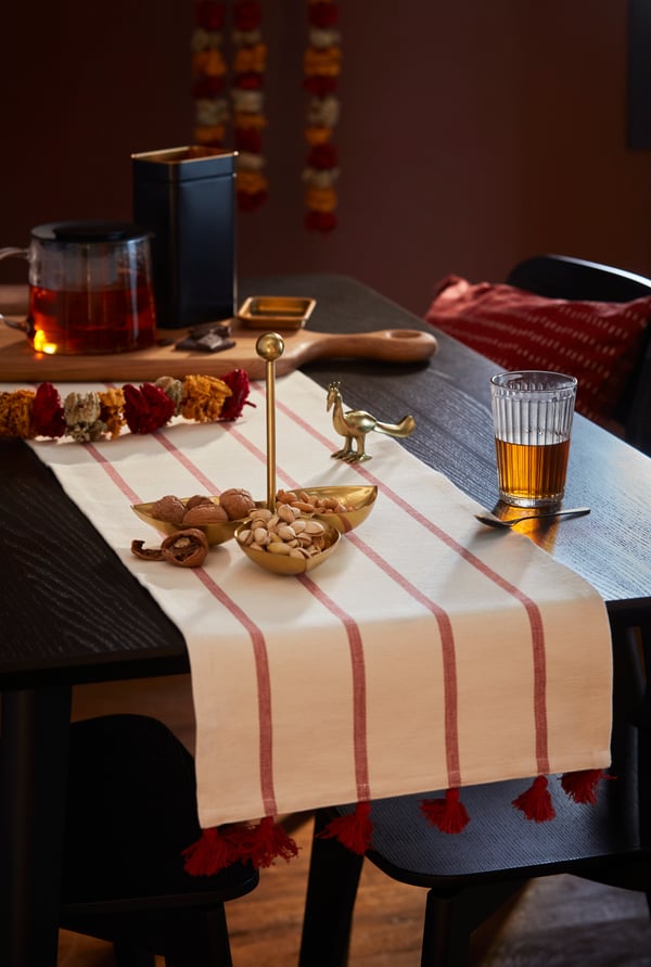 Products from the AROMATISK collection on a white and red runner, on top of a dining table.