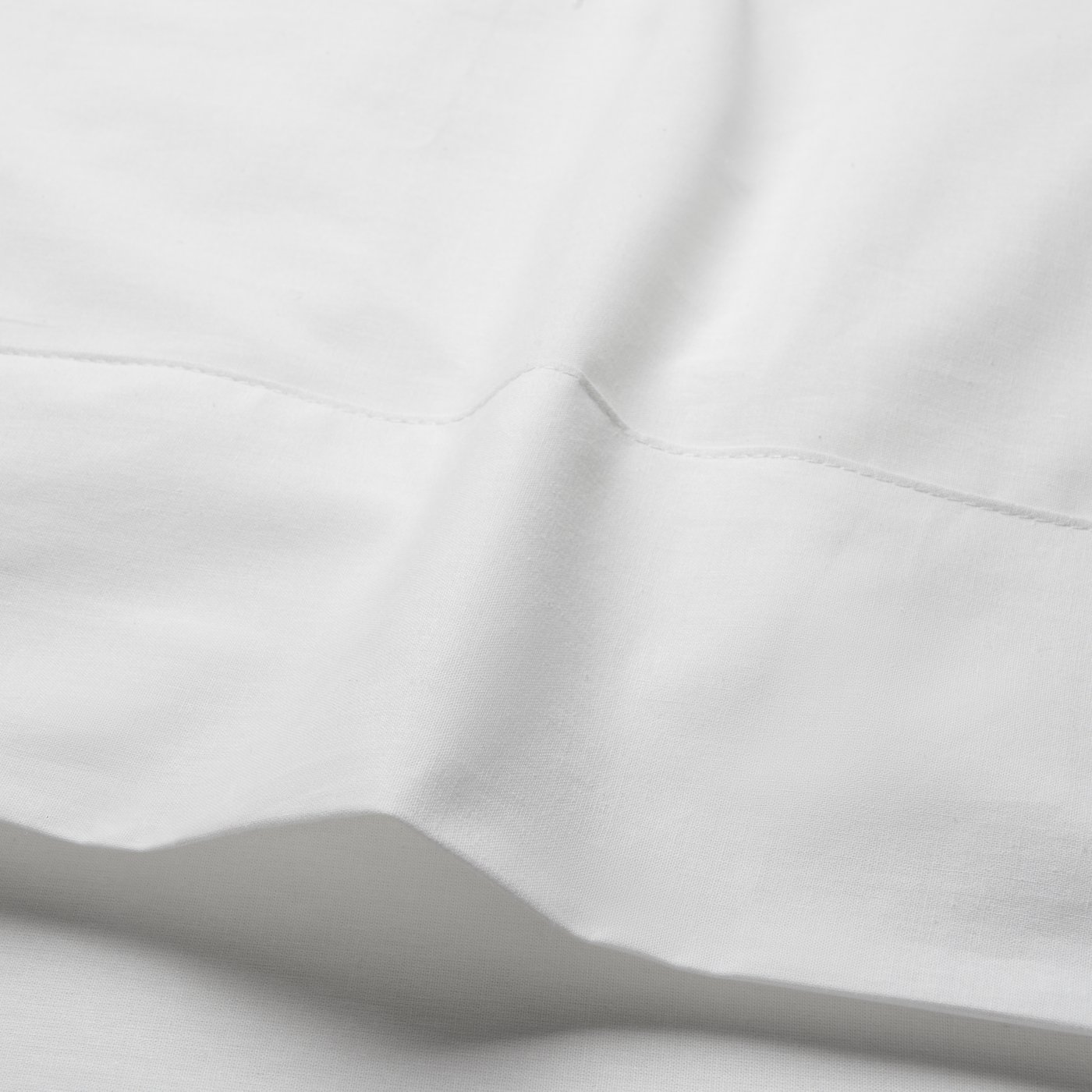 A close-up of a white DVALA flat sheet that is slightly crinkled. 
