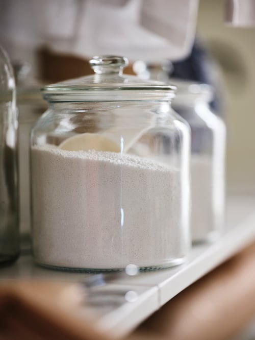 Prim plan pe raftul din bucătărie cu mai multe borcane transparente din sticlă cu capace strânse care mențin ingredientele proaspete.