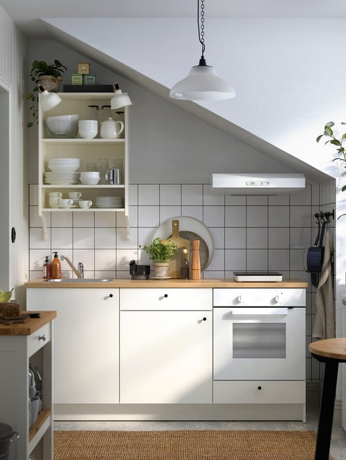 Kitchen with tiled wall, with a base cabinet with doors and drawers, a kitchen island, an oven, and a wall shelf.