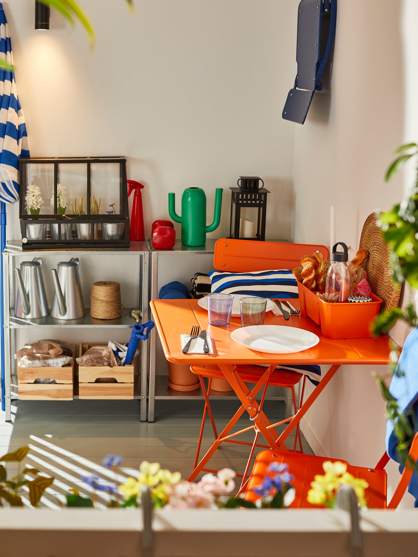 An outdoor bright orange/bright orange SUNDSÖ table and 2 folding chairs outside