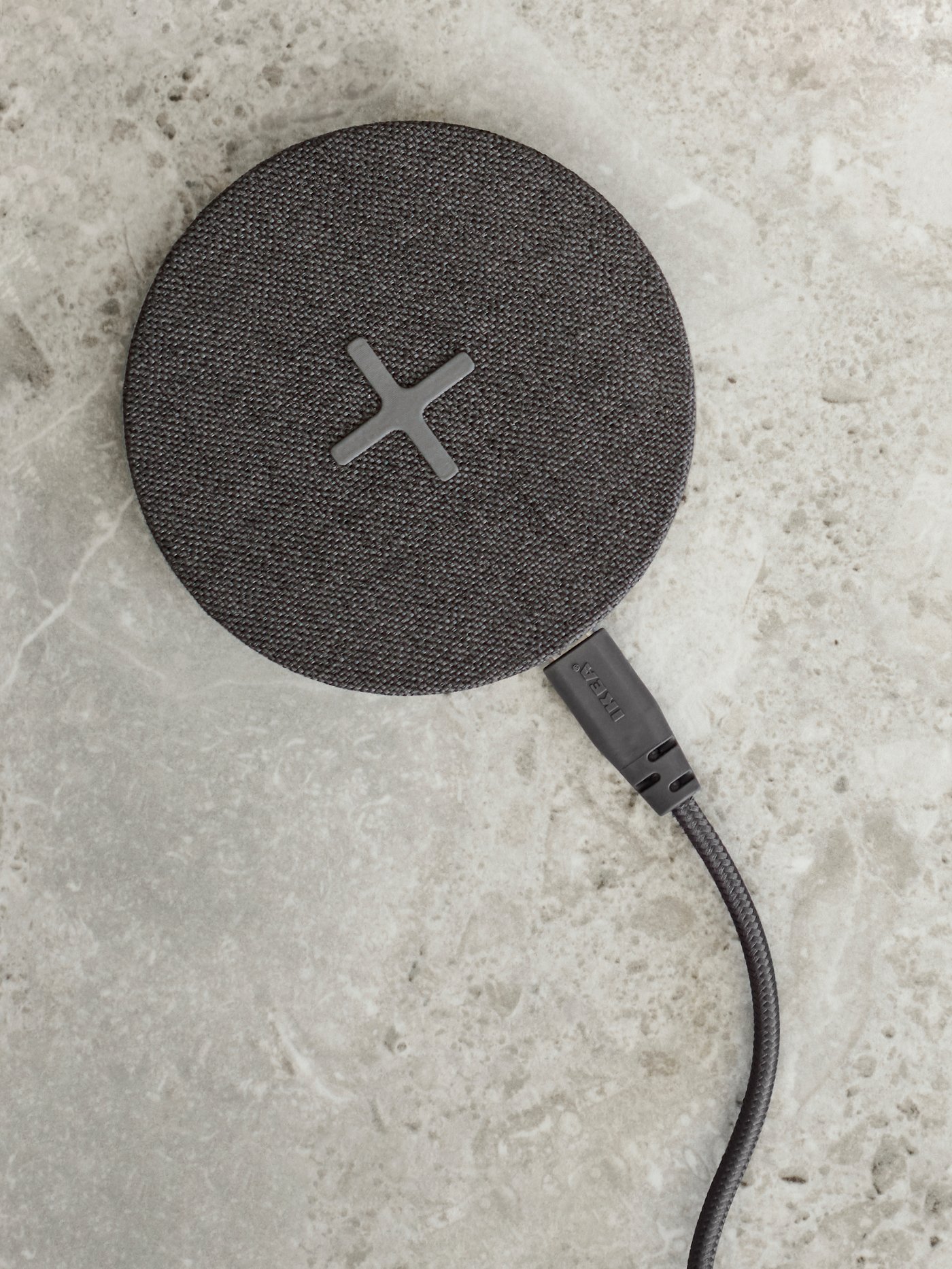 Dark gray NORDMÄRKE wireless charge on a light gray surface.