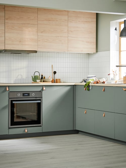 An airy kitchen has a mix of ASKERSUND light ash effect doors on wall cabinets and grey-green fronts on base cabinets.