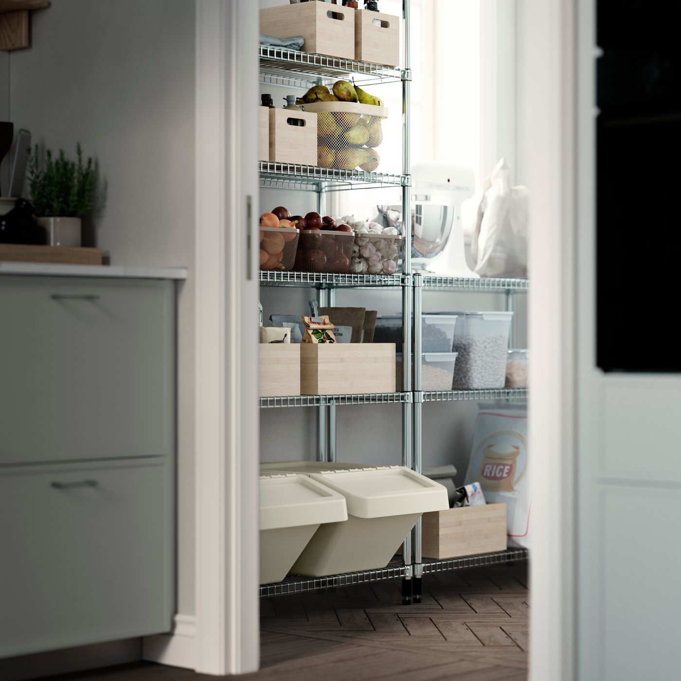 A pantry with OMAR shelving units, storing wooden boxes, glass jars, fruit baskets, dry food and a white kitchen mixer.