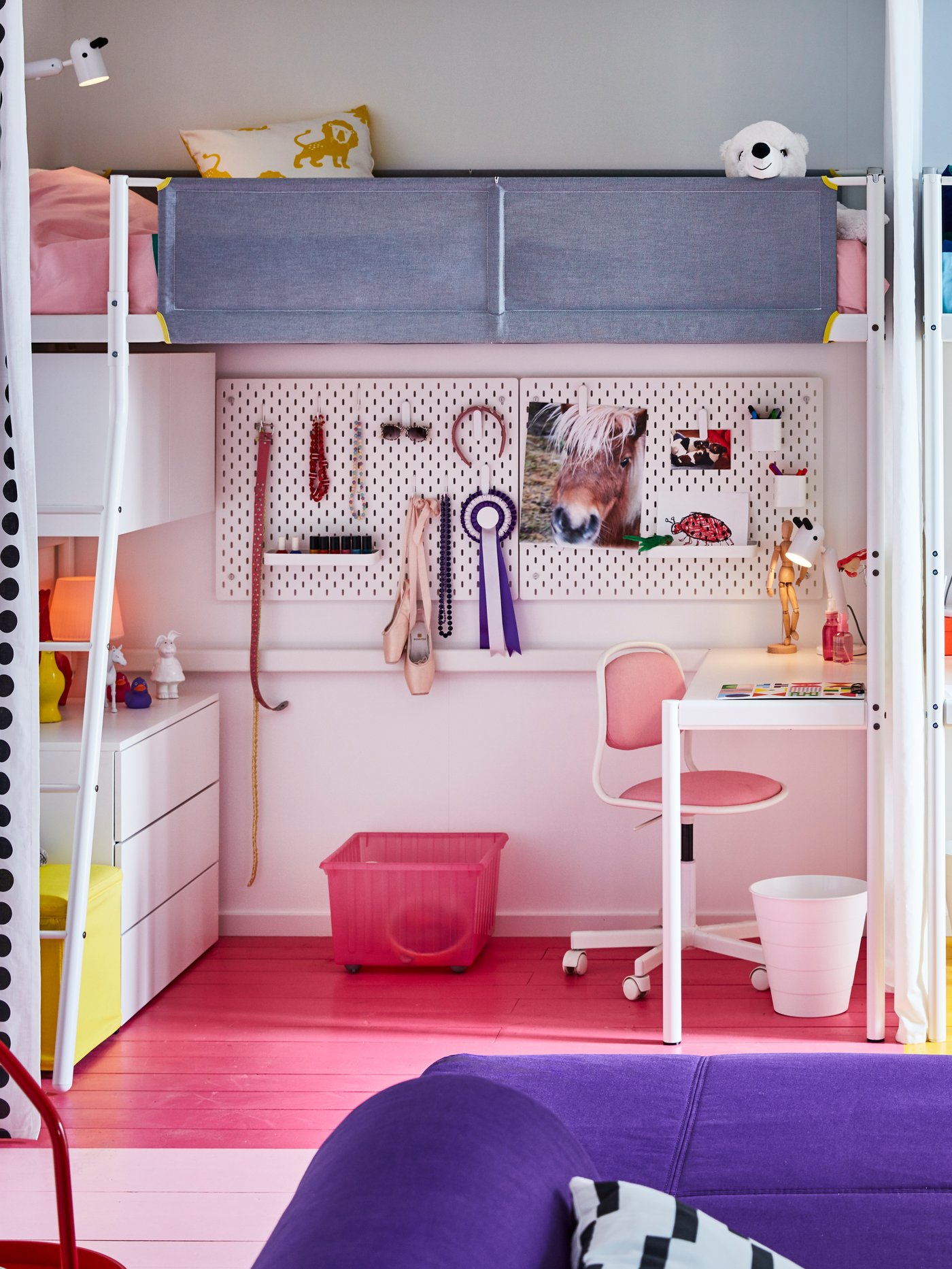 Children's room with loft bed frame, children's desk chair, pegboard combination, storage crate, chest of drawers, bin, lamp.