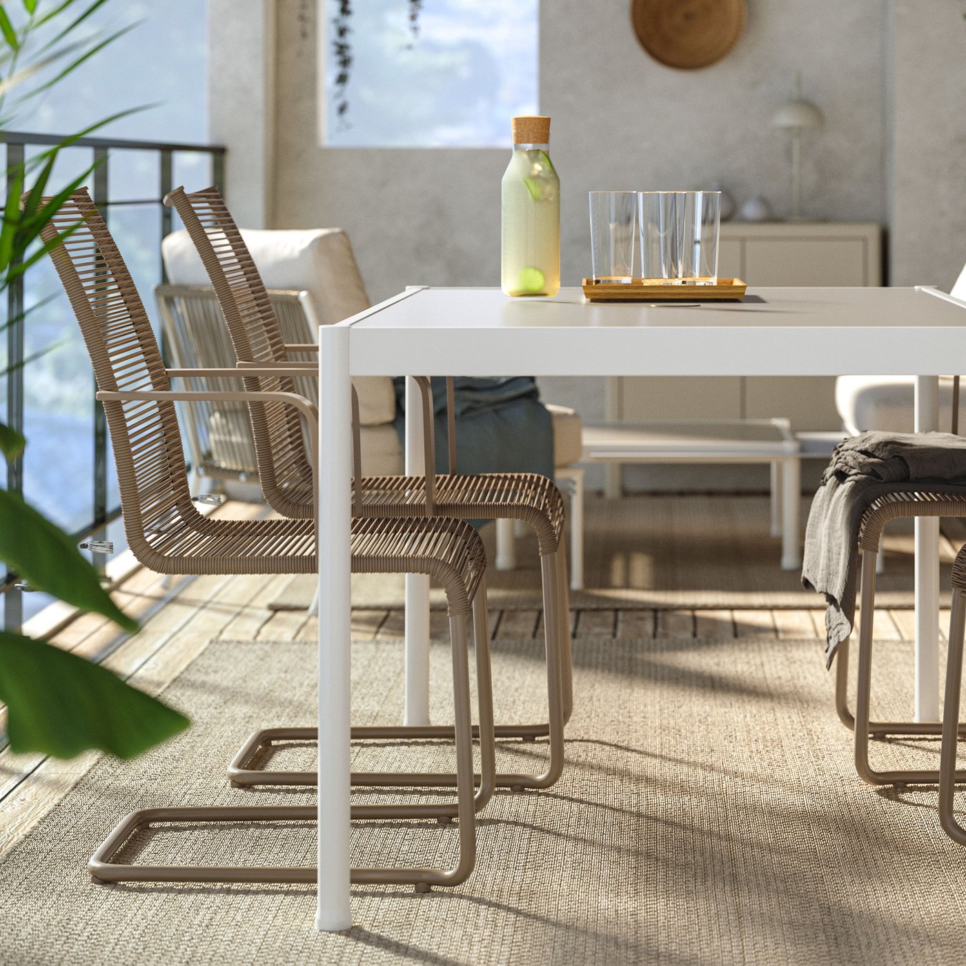 Ett vitt utebord med beige stolar stående på balkong.