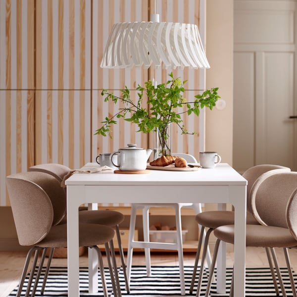 An EKEDALEN extendable table, with KRYLBO chairs and an URBAN junior chair around it, stands under an YTLÄGE pendant lamp.