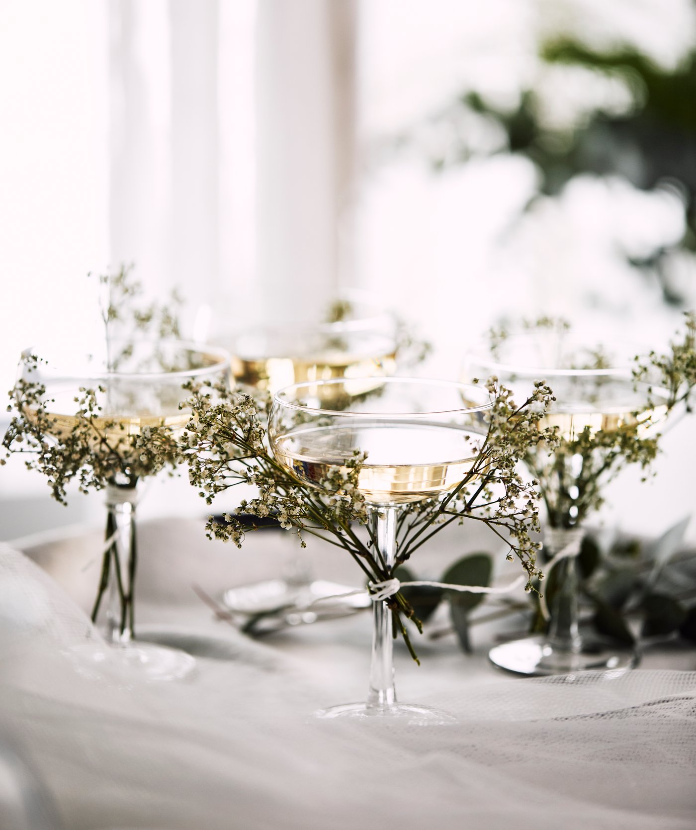 Vier STORHET Sektschalen auf einem Tablett mit kleinen Wildblumen, die um die Stiele gebunden sind.