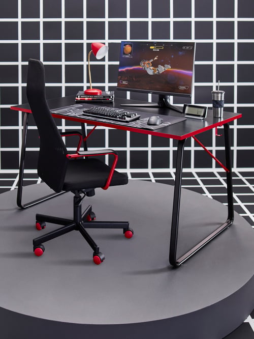 A modern workspace that features a gaming desk, a gaming chair, a mug with a lid and a straw, and an LED work lamp.