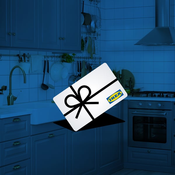 Bucătărie modernă cu dulapuri gri și cuptor încorporat. În prim-plan se află un card cadou IKEA alb, decorat cu o fundă neagră.