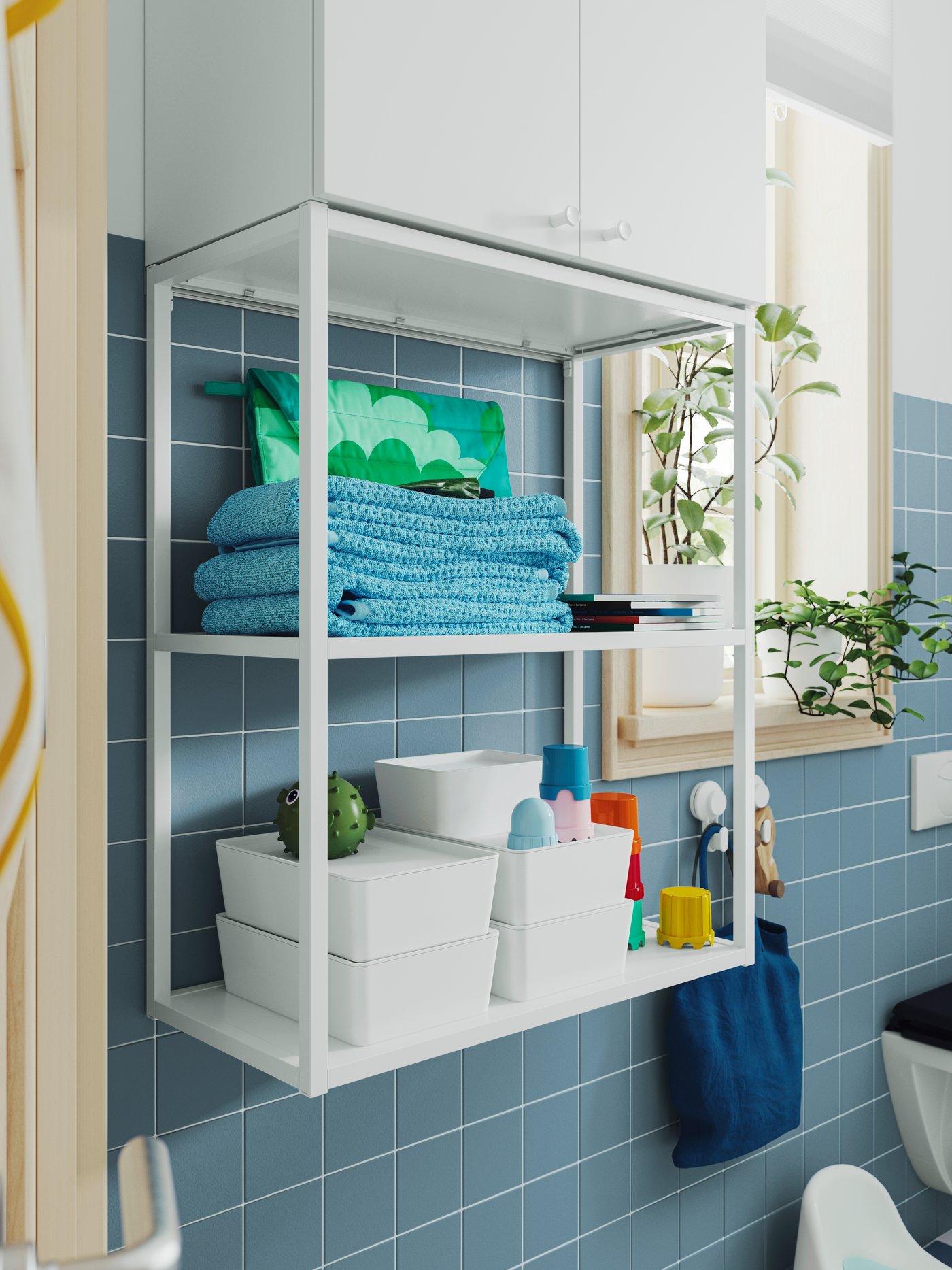 A white ENHET wall frame has shelves with KUGGIS boxes with lids, stacked on top of each other, and other bathroom products.