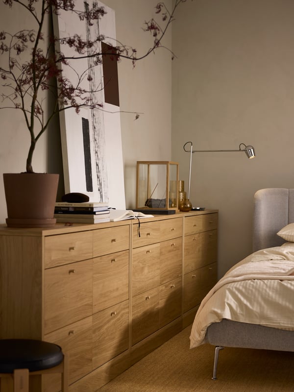 Three TONSTAD chests with 6 drawers along a beige wall with a MODERMOLN lamp and a plant in a KLARBÄR plant pot with saucer.