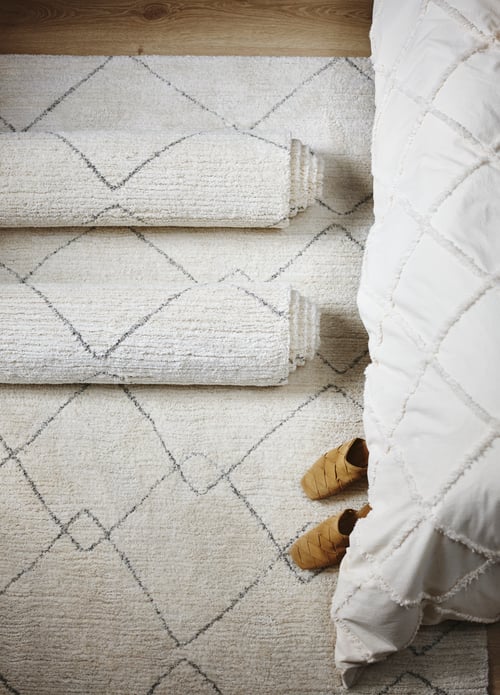 Bedroom featuring multiple rectangular TVERSTED low pile rugs made of synthetic fibre placed on a wooden surface.