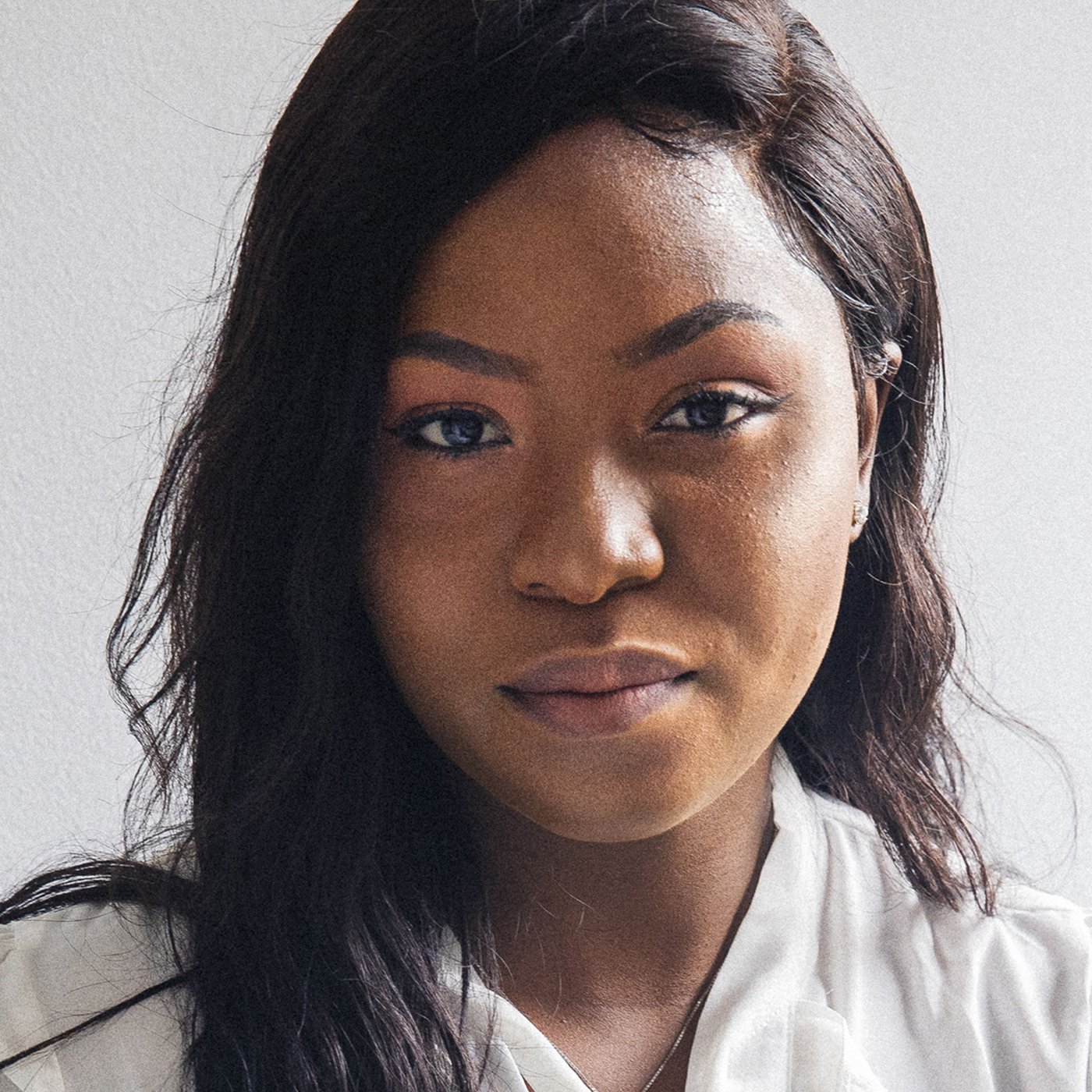 Portrait of Precious, a Nigerian refugee and IKEA Canada co-worker, wearing a white blouse.