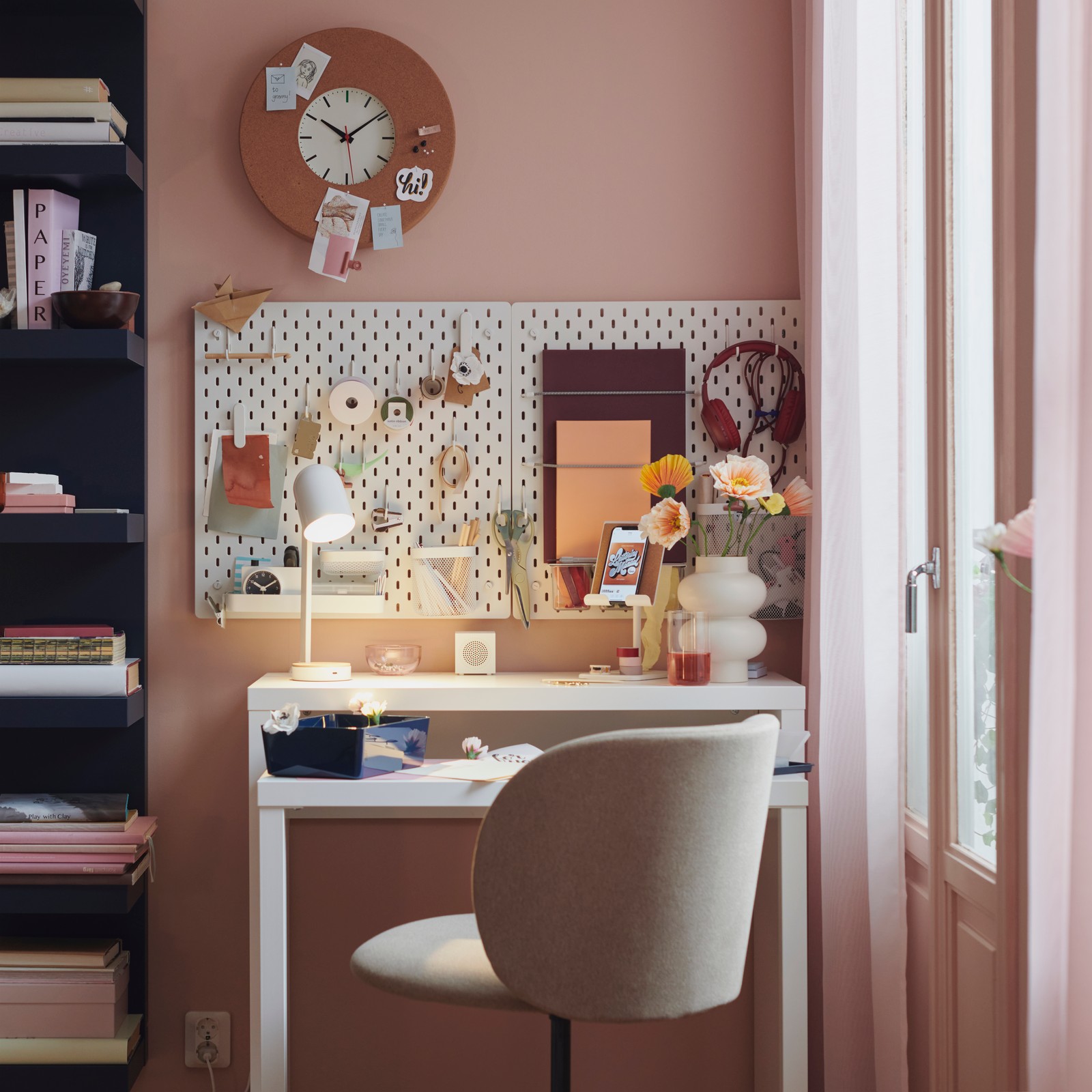 A KRYLBO swivel chair stands at a desk. On the wall above are SKÅDIS pegboards and a SVARTGÖK wall clock.