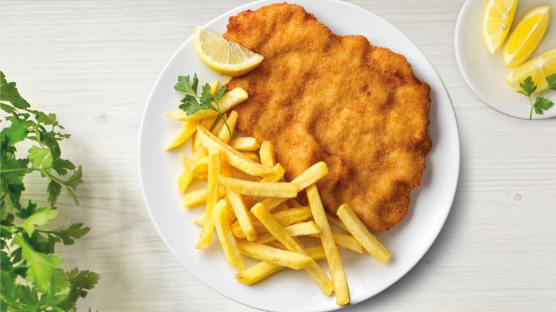 Schnitzel mit Pommes auf einem Teller mit Zitrone präsentiert.