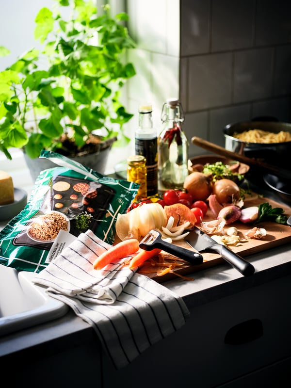 A kitchen worktop filled with ingredients mid-cooking prep, a RINNIG tea towel, and a bag of VÄRLDSKLOK plant mince.