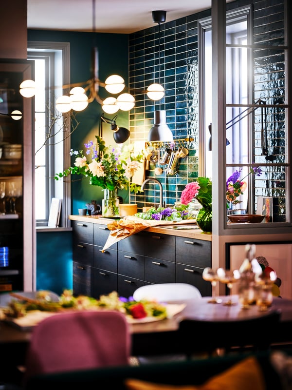 A STORSLINGA LED 8-armed chandelier illuminating a dining area with an ASKERSUND dark brown kitchen in the background.