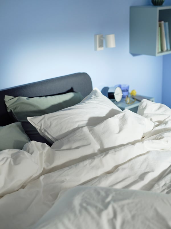 SLATTUM bed frame in blue bedroom. White bedding on top.