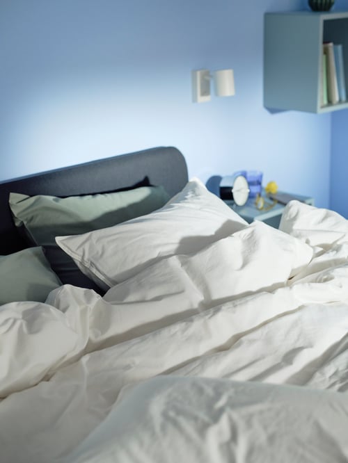 Bedroom with a white ÄNGSLILJA duvet cover and 2 pillowcases placed on a SLATTUM upholstered bed frame.