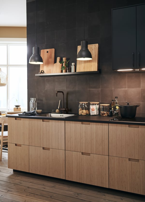 In this modern kitchen, FRÖJERED kitchen fronts in bamboo are paired with black tiled walls and accessories.