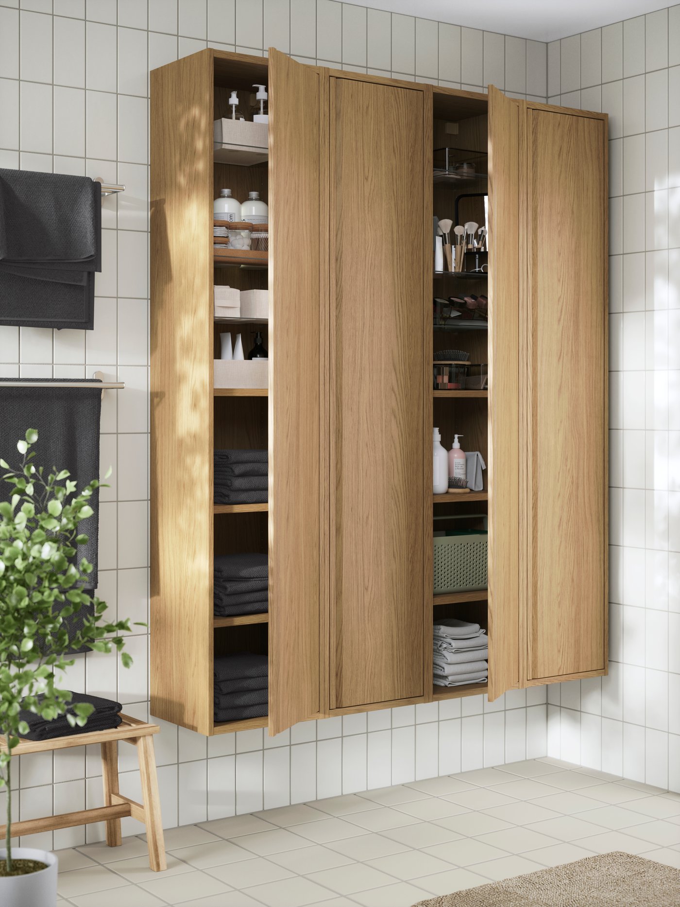 Open ÄNGSJÖN high cabinets with doors with neatly organised towels, toiletries, and bathroom essentials.