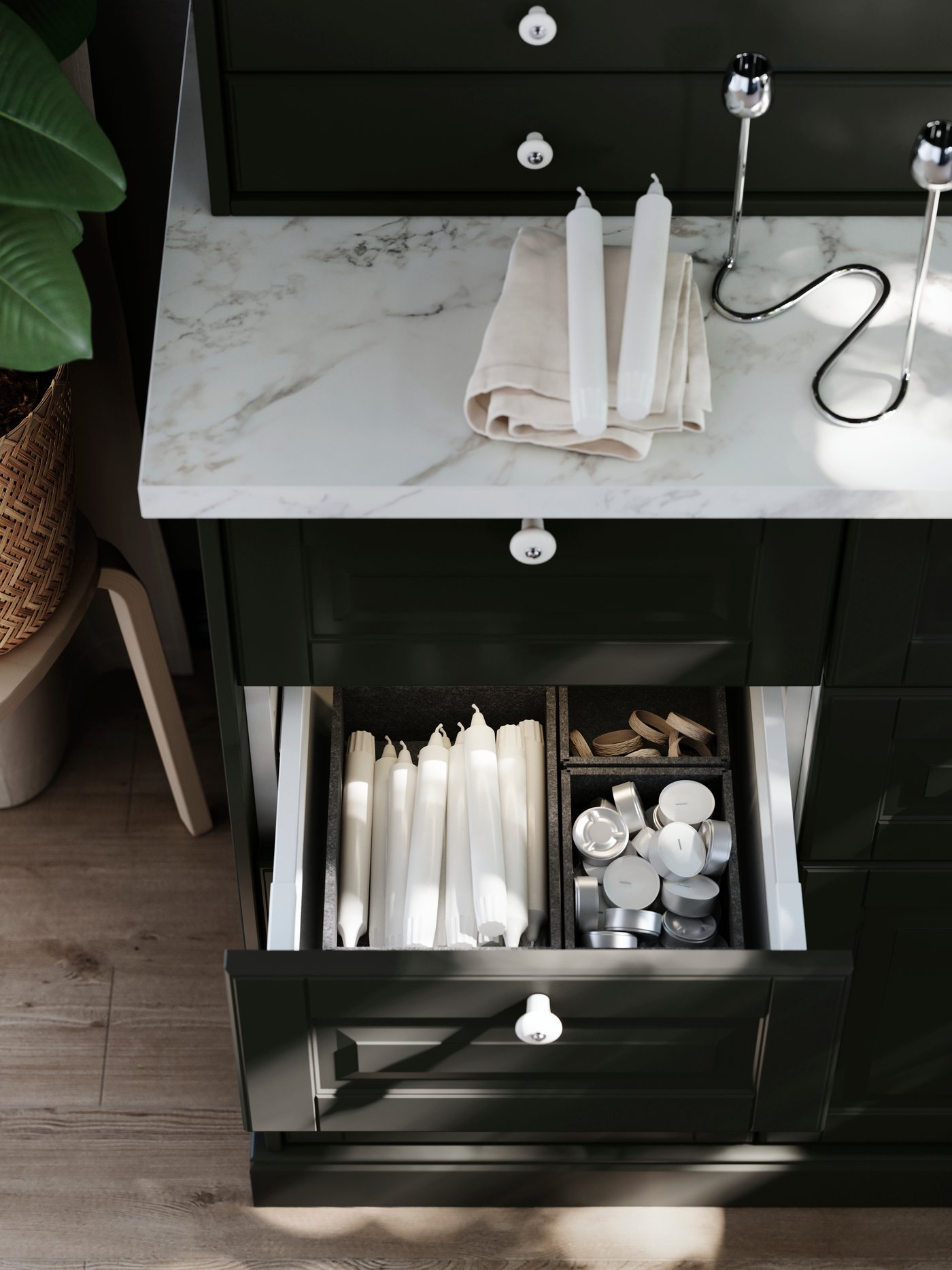 Un cassetto aperto in un mobile con frontali BODBYN neri contenente alcuni accessori interni nei quali sono organizzati articoli per la zona pranzo.