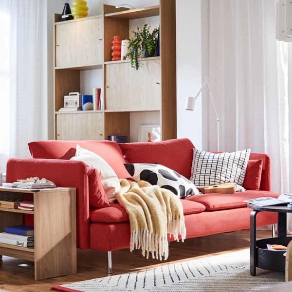 A red SÖDERHAMN sofa and a HOLMERUD side table stand in a living room in front of a LÅDMAKARE storage combination.