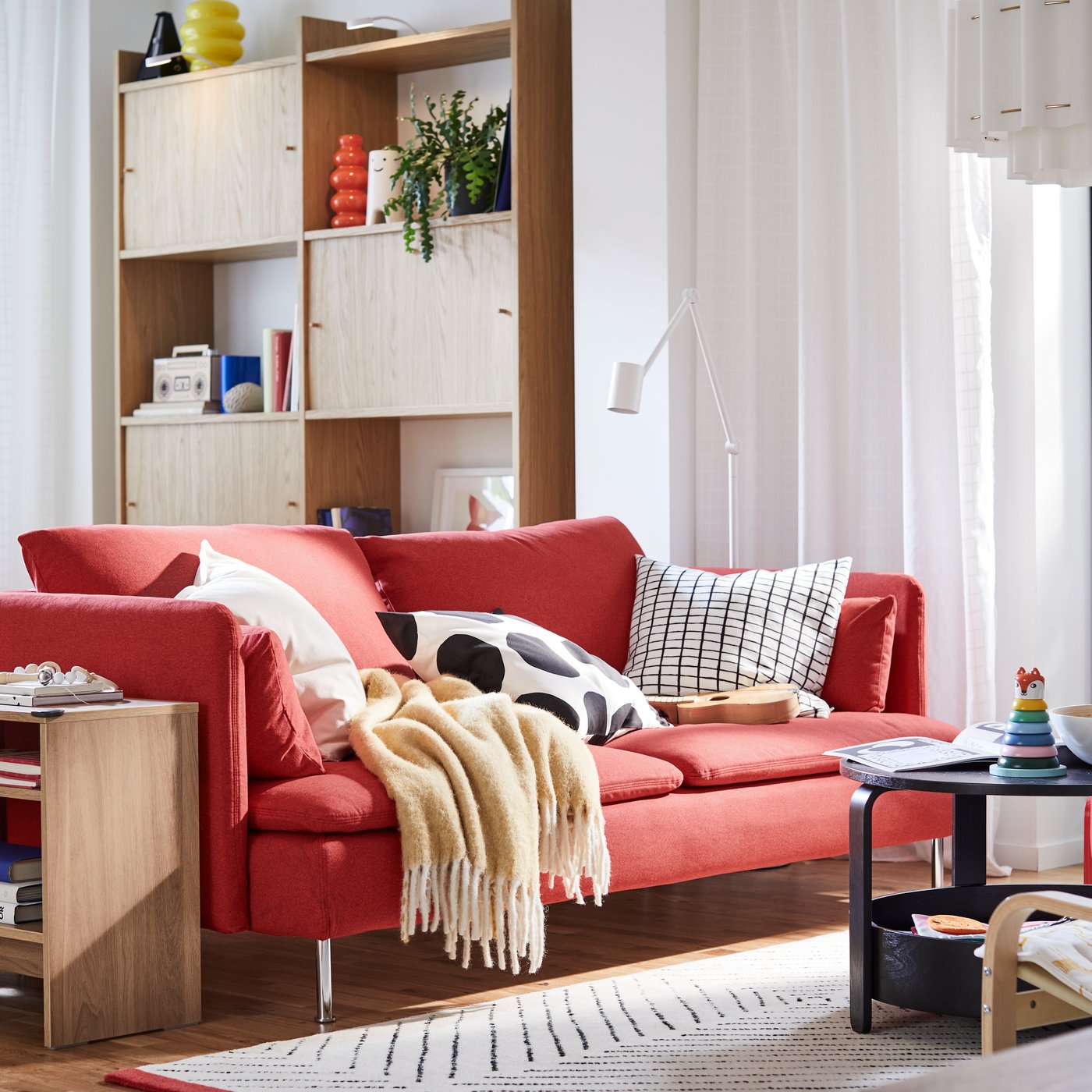 A red SÖDERHAMN sofa and a HOLMERUD side table stand in a living room in front of a LÅDMAKARE storage combination.
