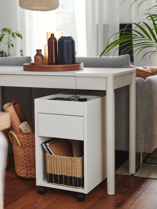 A TONSTAD drawer unit on castors. This unit is placed underneath a desk that has a tray on it, which is holding vases.