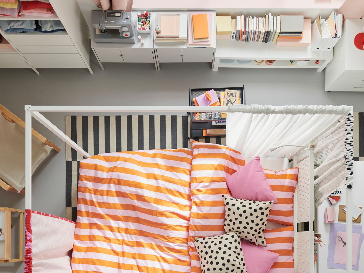 Vue d’ensemble d’une chambre à coucher colorée. Un lit à baldaquin VITARNA blanc est placé au centre, garni de linge de lit SLÅNHÖSTMAL.