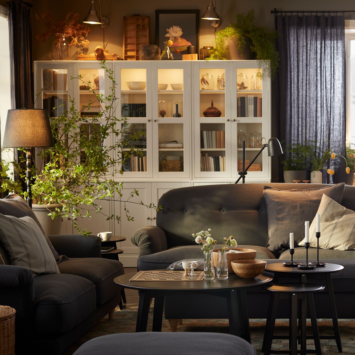 A farmhouse-style living room with plenty of framed works of art and books, two ESSEBODA sofas and some KRAGSTA tables.