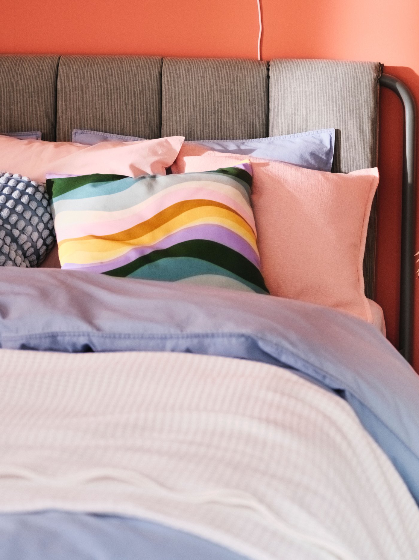 Una cama con cojines y ropa de cama de diferentes colores.
