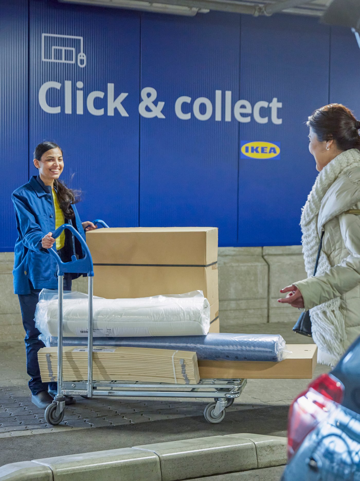 Zwei Personen übergeben einen vollgepackten Einkaufswagen.